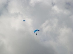 Two sky-divers with blue parachutes in cloudy sky